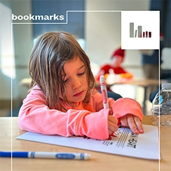 A young child colors with a pink marker