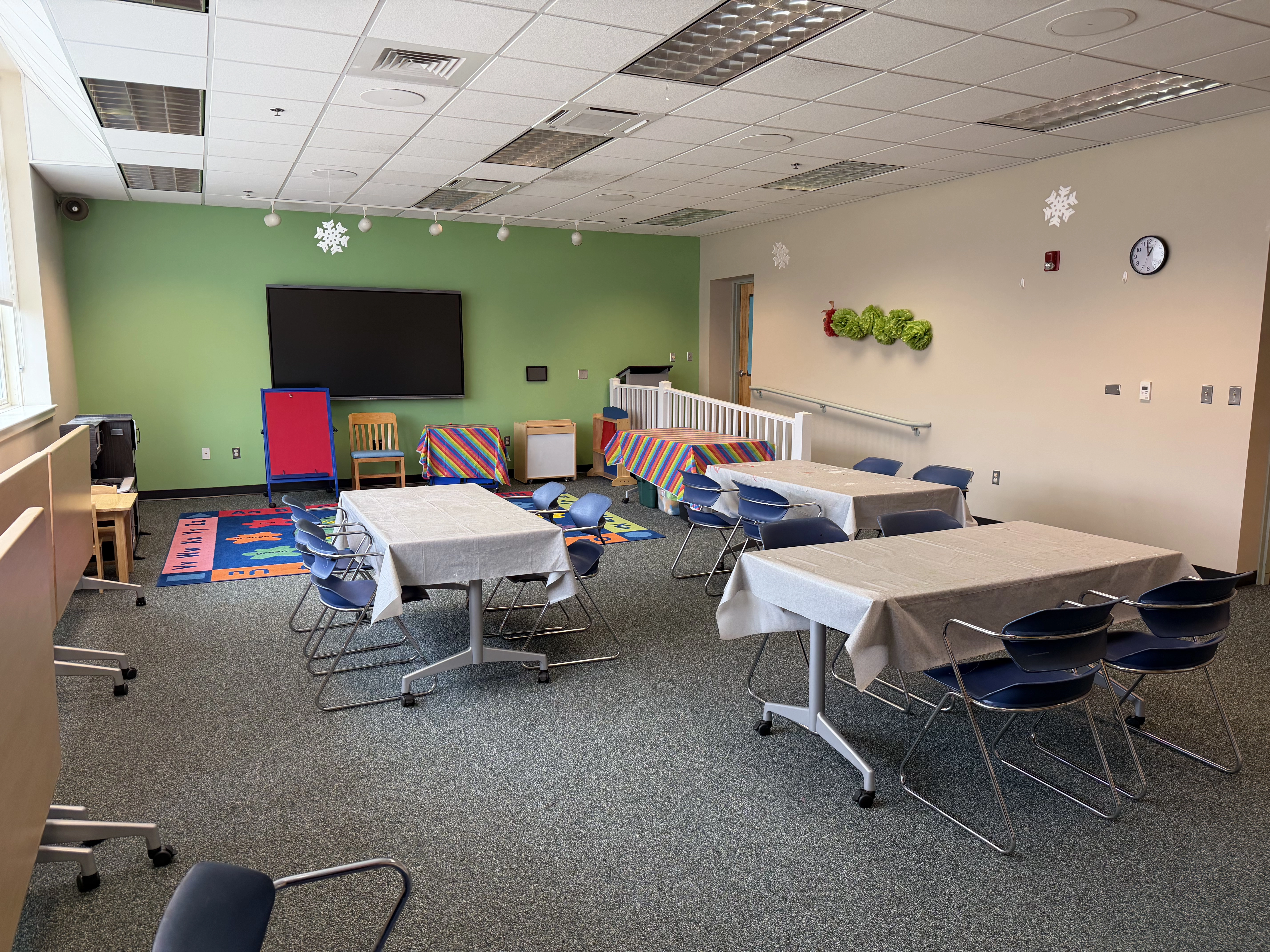 A view of the room from the windows showing the green back wall and a room full of tables