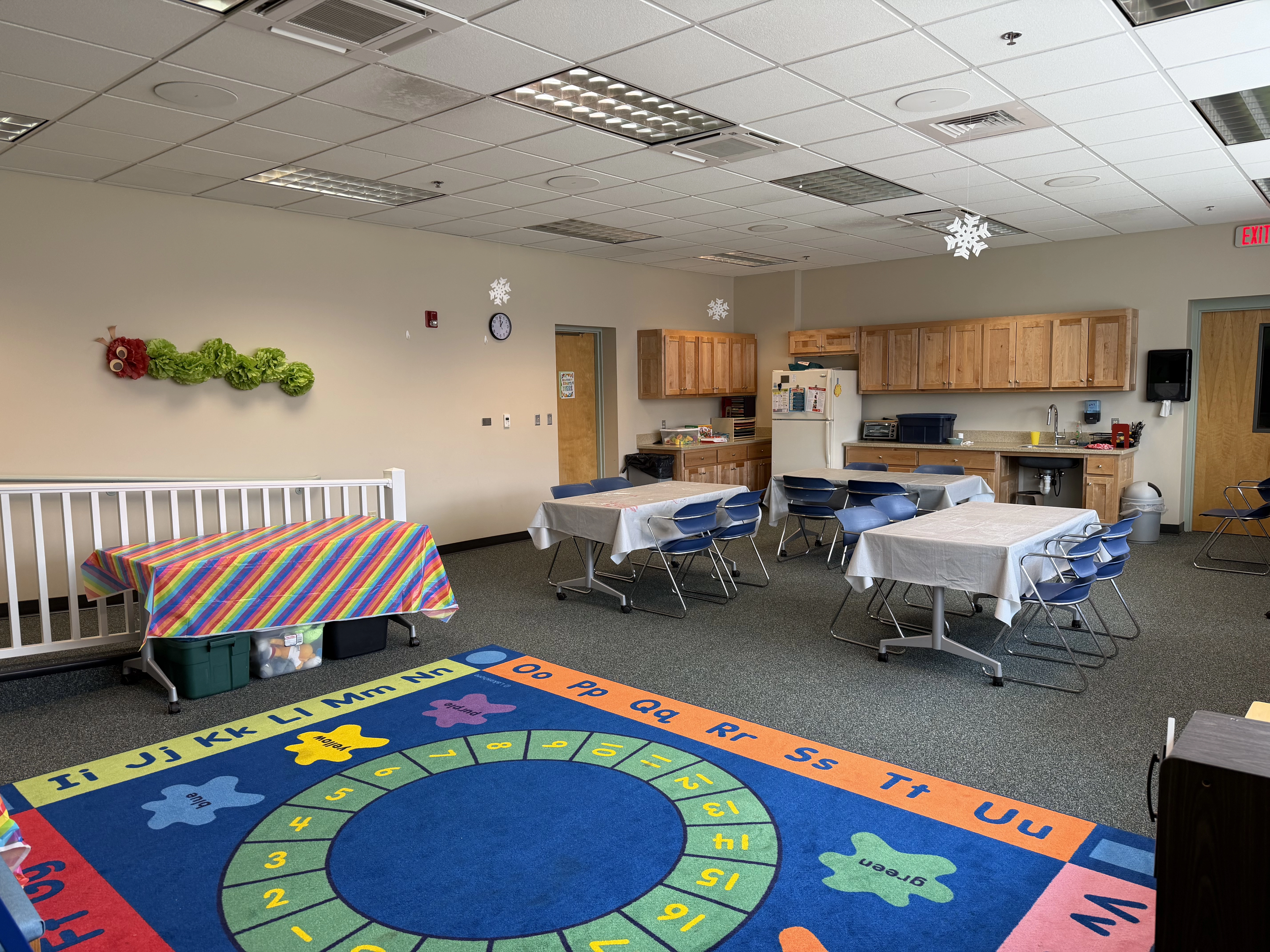 a view of the room from the green back wall showing the full room with tables and the kitchen in the background