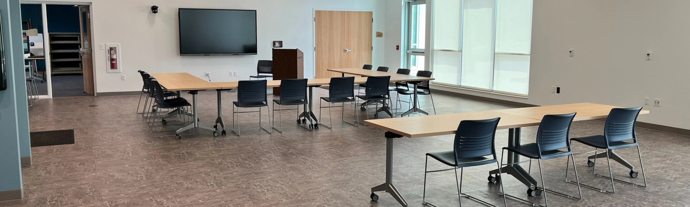 Community Room showing tables, chairs and a monitor on the wall