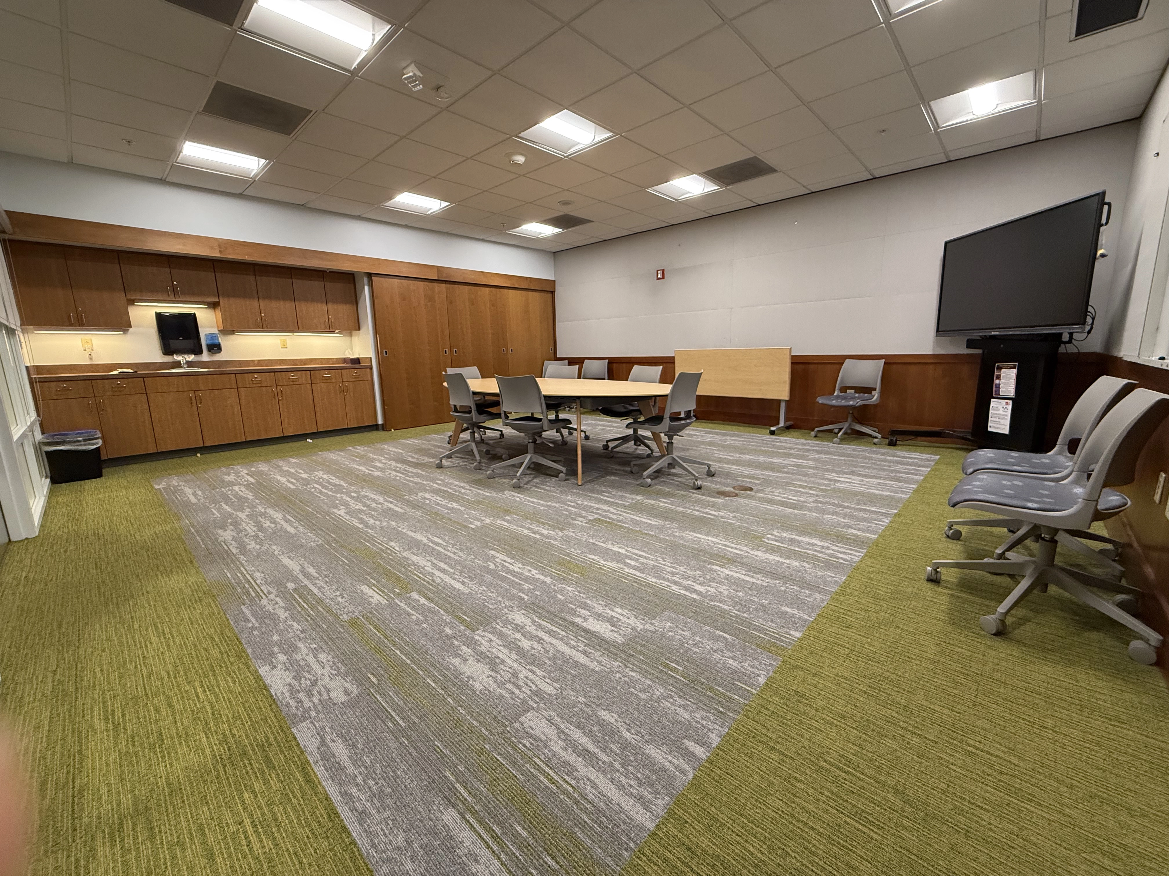 A view of the Trust Room from inside right corner, showing the kitchen area, the table and chairs