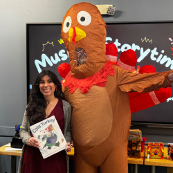 A librarian poses next to a turkey mascot
