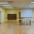 A large brightly lit space with a projector screen, table, chairs and yellow walls