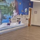 a view of the room with a brightly colored mural on the left hand wall and a movable display on the right