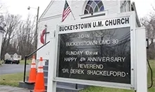 Sign for Buckeystown U.M. Church in front of a white church with beautiful stainglass windows